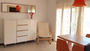 A room with a white wardrobe, a wooden chair, a wooden dining table, and a red pendant light.