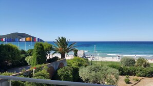 A coastal view with flags, beach, and greenery. - Apartment in front of the beach, superb sea view and terrace 🏖️🏖️🏖️ (Saint-Cyr-sur-Mer)