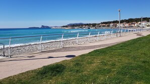 A coastal promenade with a pebble beach, a clear blue sea, and a row of buildings in the background. - Apartment in front of the beach, superb sea view and terrace 🏖️🏖️🏖️ (Saint-Cyr-sur-Mer)