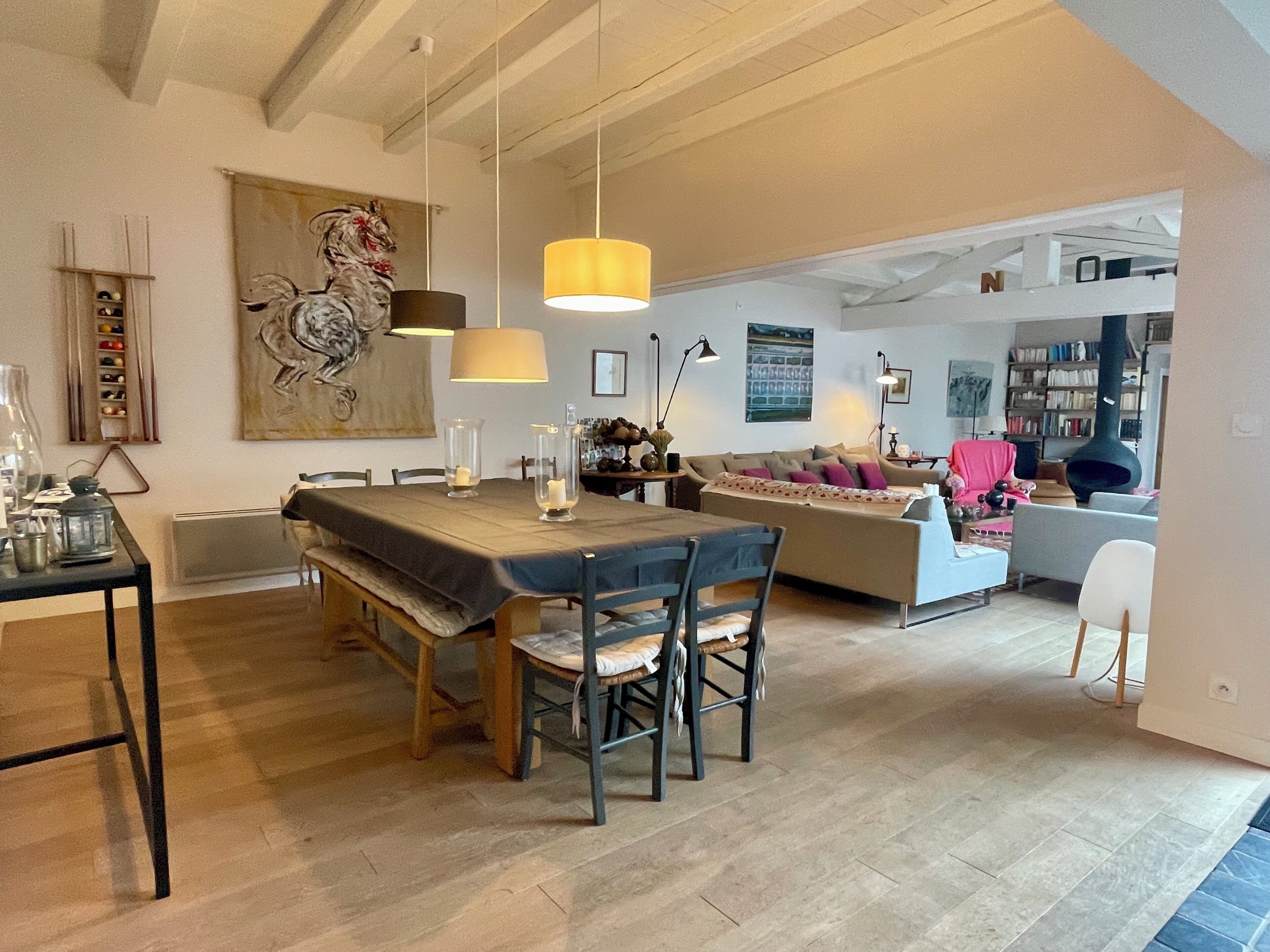 Een ruime woonkamer met een eettafel, stoelen, een bank en een keuken op de achtergrond.