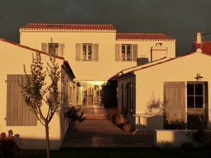 Ein zweigeschossiges Haus mit Holzterrasse, Glastür und einer kleinen Patio.