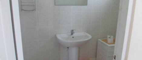 A small bathroom with a white sink, a mirror, and a toilet.