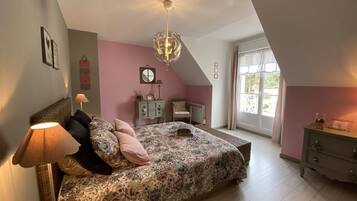 A bedroom with a bed, a dresser, a lamp, a ceiling fan, and a window with curtains.