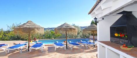 A pool area with lounge chairs and a barbecue grill.