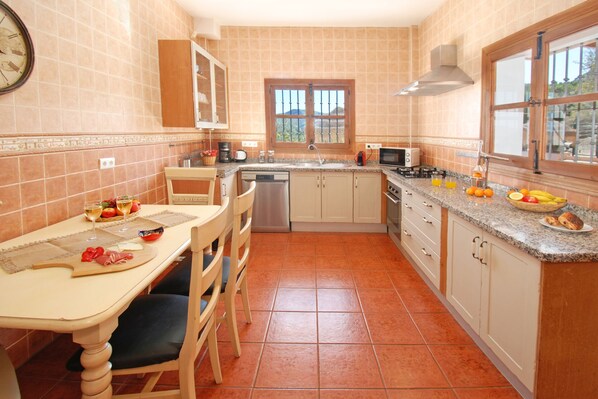 Una cocina con una mesa de comedor, sillas, un lavamanos, una estufa y una ventana.