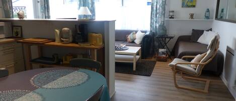 A cozy living room with a dining area, a sofa, a chair, and a small table.