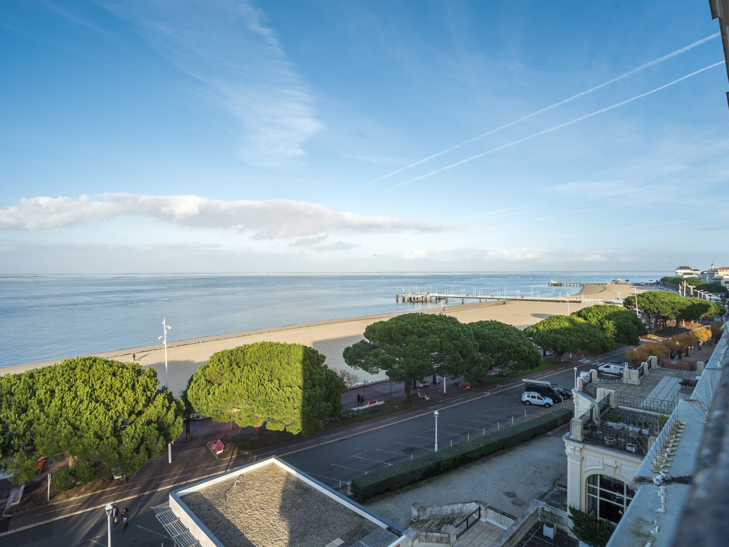 Une vue sur la côte, avec une plage, des arbres et une jetée.
