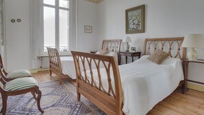 A bedroom with two wooden beds, a window, a radiator, a chair, and a table with lamps. - Apartment for 5 in Arcachon with secure parking (Arcachon)
