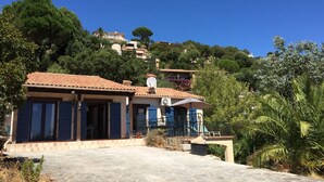 A villa with a tiled roof, a balcony, and a view of the surrounding hills. - Villa Trémière - Sea view and 28 ° C heated swimming pool (Cavalaire-Sur-Mer)