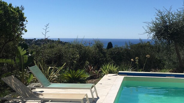 A pool with a clear view of the ocean, surrounded by greenery and lounge chairs. - Villa Trémière - Sea view and 28 ° C heated swimming pool (Cavalaire-Sur-Mer)