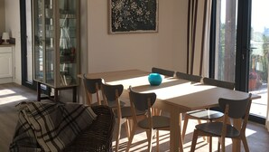 A dining area with a wooden table, chairs, and a blue vase. There is a glass cabinet with dishes and a painting on the wall. - Villa Trémière - Sea view and 28 ° C heated swimming pool (Cavalaire-Sur-Mer)
