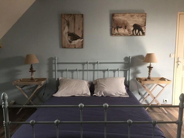 A bedroom with a metal bed frame, two bedside tables with lamps, a wooden headboard, and two wall-mounted artworks depicting animals. - COTENTIN, SEASIDE, NICE INDEPENDENT COUNTRY CLASS 4 STARS 8 PEOPLE (Réville)