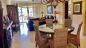 A dining area with wicker chairs, a glass table, and a chandelier. - Book a spectacular ocean view 5 star resort !  (Cabo San Lucas)