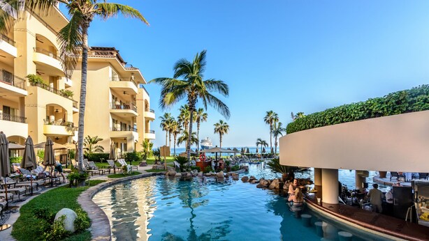 A resort pool area with lounge chairs, palm trees, and a bar. - Book a spectacular ocean view 5 star resort !  (Cabo San Lucas)