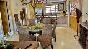 A dining area with wicker chairs, a glass-top table, and a chandelier. - Book a spectacular ocean view 5 star resort !  (Cabo San Lucas)