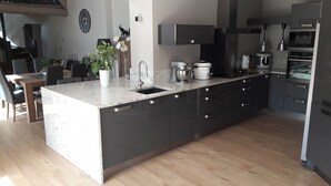 Eine moderne Küche mit Granit Arbeitsplatte, Edelstahlgeräten und einem Essbereich aus Holz.