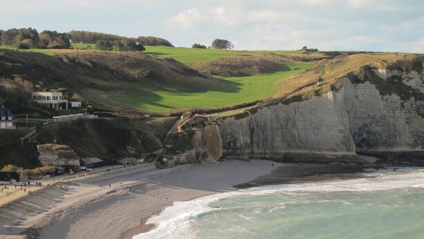 Paisaje costero con acantilados, una playa y un campo de golf.