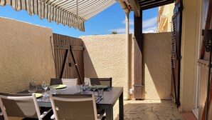 Eine Terrassenanlage mit Esstisch, Steinboden und Holzzaun.