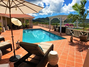 A swimming pool with a patio area, including lounge chairs and a pergola. - HIGH DEMAND. POOL, WALK TO BEACH, PANORAMIC SEA VIEWS, OVERLOOKS JOLLY HARBOUR (Jennings)