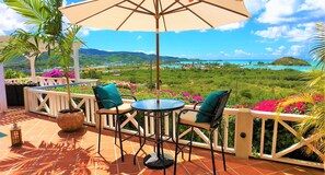 A terrace with a table and chairs, a potted plant, and a view of a coastal landscape. - HIGH DEMAND. POOL, WALK TO BEACH, PANORAMIC SEA VIEWS, OVERLOOKS JOLLY HARBOUR (Jennings)