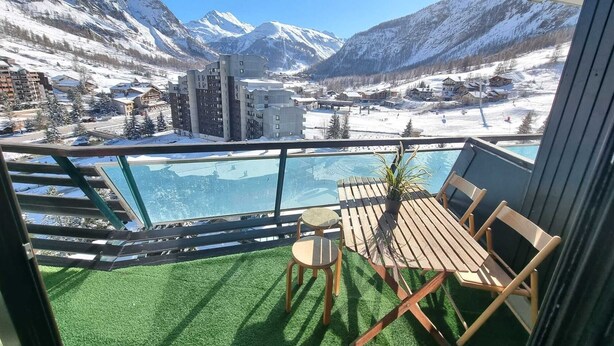 A balcony with a view of snow-covered mountains, a pool, and a small table with chairs. - Splendid apartment at the foot of the slopes/2 separate bedrooms/ ideal for a 4p family (Val-d'Isère)