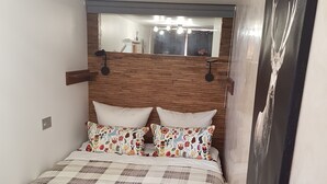 A bedroom with a wooden headboard, a plaid bedspread, and a large mirror above the bed. - Splendid apartment at the foot of the slopes/2 separate bedrooms/ ideal for a 4p family (Val-d'Isère)