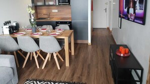A modern kitchen with a microwave, oven, and sink. There is a dining table with chairs and a vase of flowers. A television is mounted on the wall. - Splendid apartment at the foot of the slopes/2 separate bedrooms/ ideal for a 4p family (Val-d'Isère)