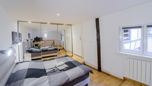 Une chambre à coucher avec un lit, des lampes de chevet, un miroir, une armoire et une fenêtre.