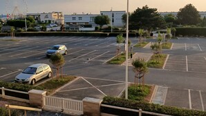 En parkeringsplads med flere biler, et pariserhjul og bygninger i baggrunden.