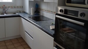 Et køkken med hvide skabe, en sort bordplade, en mikroovn og en ovn.