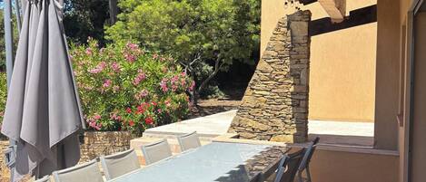 Une terrasse extérieure avec une table et des chaises, une pergola et un mur en pierre.