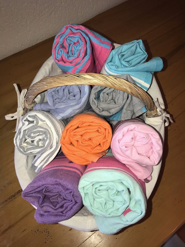 Een mand gevuld met verschillende opgerolde handdoeken in diverse kleuren.