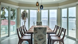 A dining area with a large table and chairs, large windows with a view of the water, and a ceiling light fixture. - Paradise Bay - 4 Bedrooms [with 2 Master Suites] & 4 Bathrooms - sleeps 10 (Marathon)