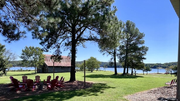 Una propiedad junto al lago con una cabaña rústica, asientos al aire libre y una vista despejada del lago.