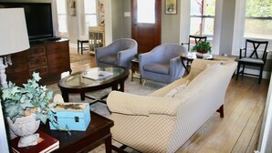 Una sala de estar con un sofá, dos sillones, una mesa de centro y una televisión.