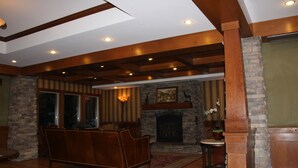 A cozy living room with a fireplace, wooden beams, stone walls, and a comfortable sofa.