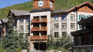 A building with a clock tower, multiple balconies, and a ski lodge facade.
