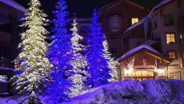 A snow-covered landscape with illuminated trees and a lodge named 'Powderhorn Lodge'.
