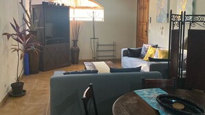 A cozy living area with a wooden ceiling, a ceiling fan, a dining table with chairs, a sofa, and a TV. - Large condo. Home away from home! (Sámara)