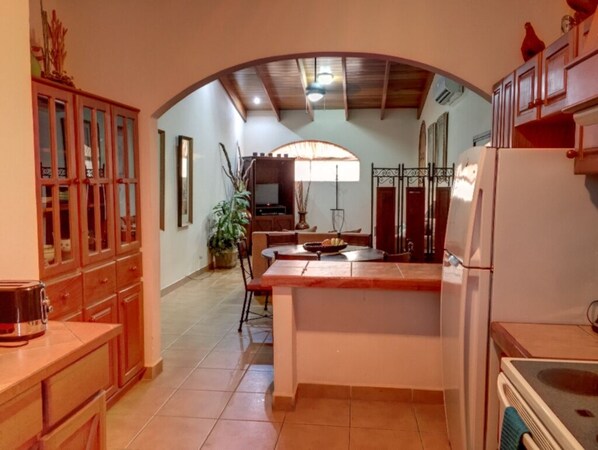 A kitchen with a central island, wooden cabinets, and a dining area with a table and chairs. - Large condo. Home away from home! (Sámara)