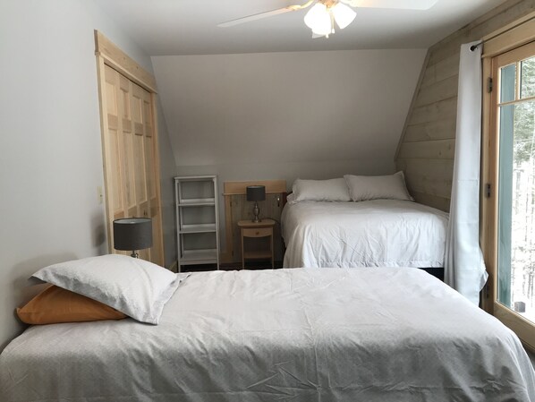 Une chambre avec deux lits, une table de chevet, une lampe et une fenêtre avec des rideaux.