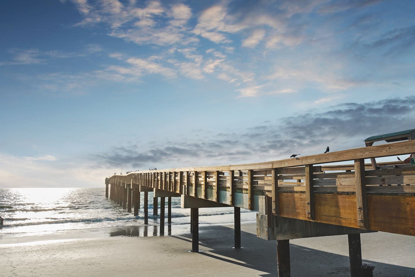 A wooden pier extending into the sea with a clear sky above.
