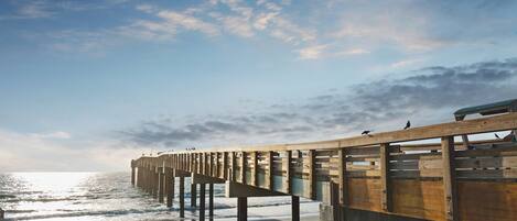 A wooden pier extending into the sea with a clear sky above.
