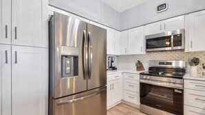 A modern kitchen with stainless steel appliances, white cabinetry, and a built-in microwave. - Atlantis 302D - Steps to the Ocean (St Augustine Beach)