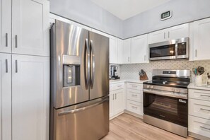 A modern kitchen with stainless steel appliances, white cabinetry, and a built-in microwave. - Atlantis 302D - Steps to the Ocean (St Augustine Beach)