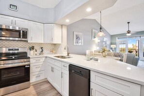 A modern kitchen with white cabinetry, stainless steel appliances, and a large island.