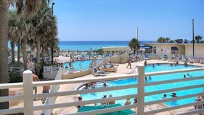A pool area with multiple swimming pools, lounge chairs, and palm trees. - 8th floor beach front condo in Tides @ Tops'l (Miramar Beach)