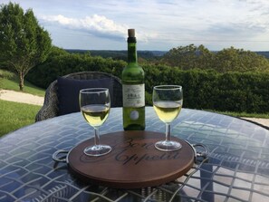 A table with a bottle of wine and two glasses on a round table with a view of the countryside. - Views, air conditioned, heated pool, chefs kitchen,Saturday check-in out (Plazac)