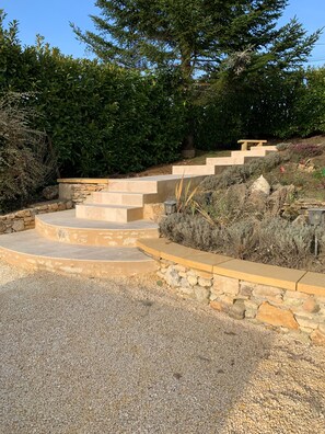 A stone staircase leading up to a seating area surrounded by gravel and vegetation.