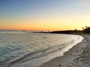Une plage aux eaux calmes, avec un rivage sablonneux et un ciel dégagé.